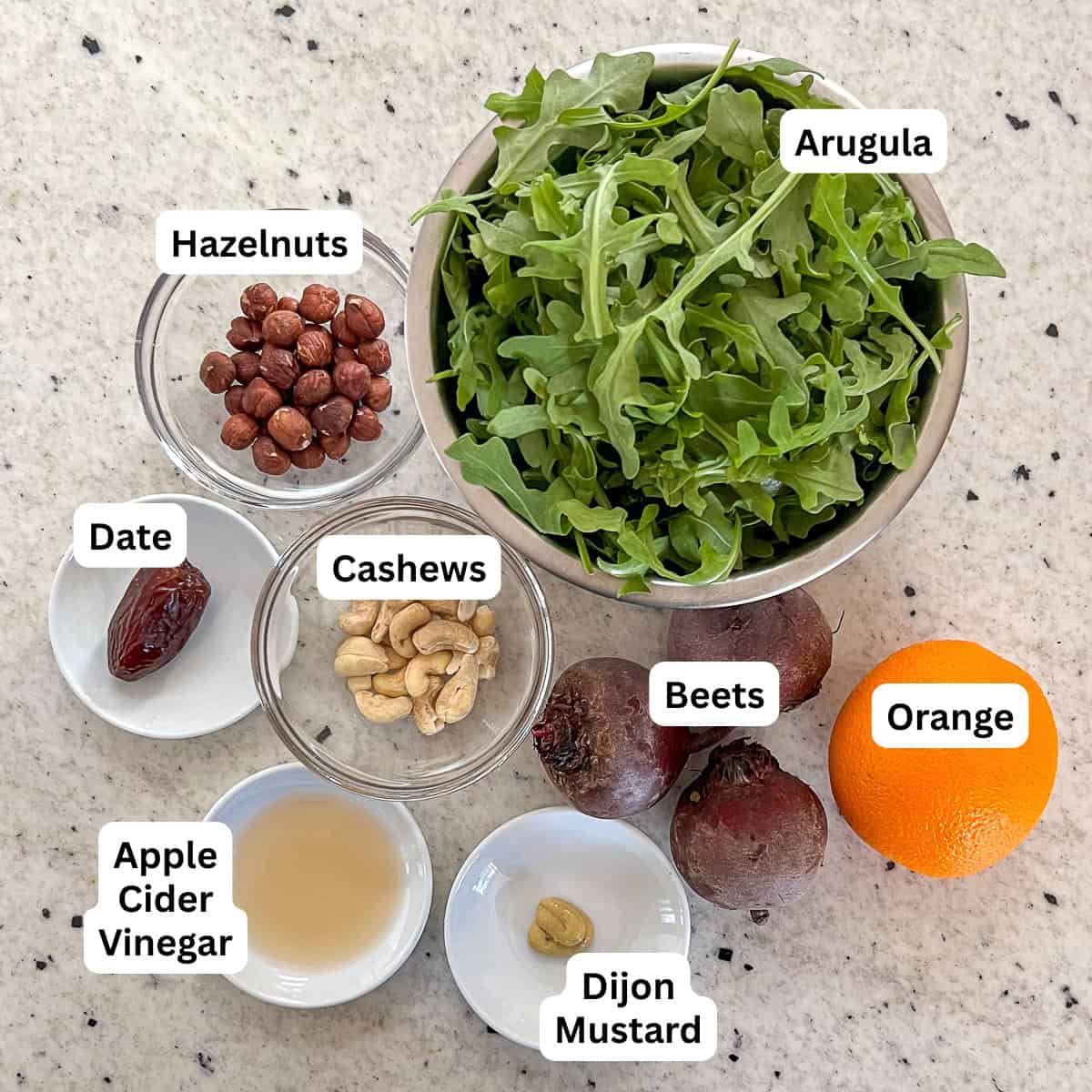 Ingredients for salad: arugula, beets, orange, hazelnuts, cashews, date, Dijon mustard, and apple cider vinegar.