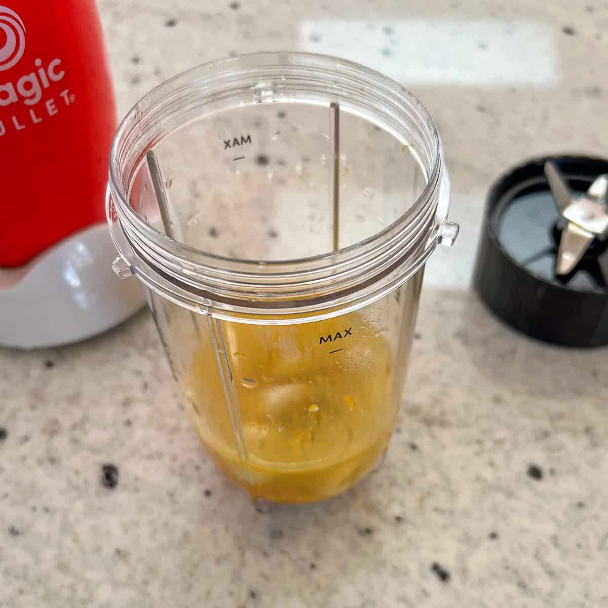 Ingredients for the citrus orange dressing in a mini bullet blender cup prior to blending.