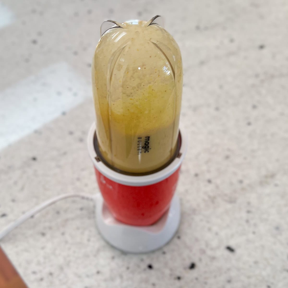 Dressing ingredients being blended in a mini bullet blender.