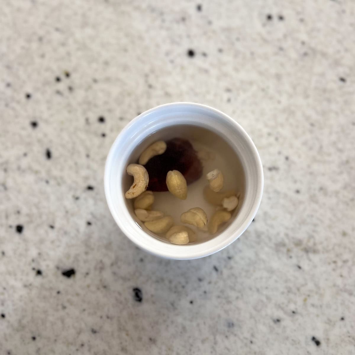 A pitted date and cashews soaking in hot water to soften.