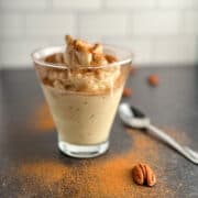 side view of banana nice cream with cinnamon and pecans in a glass with spoon on the side