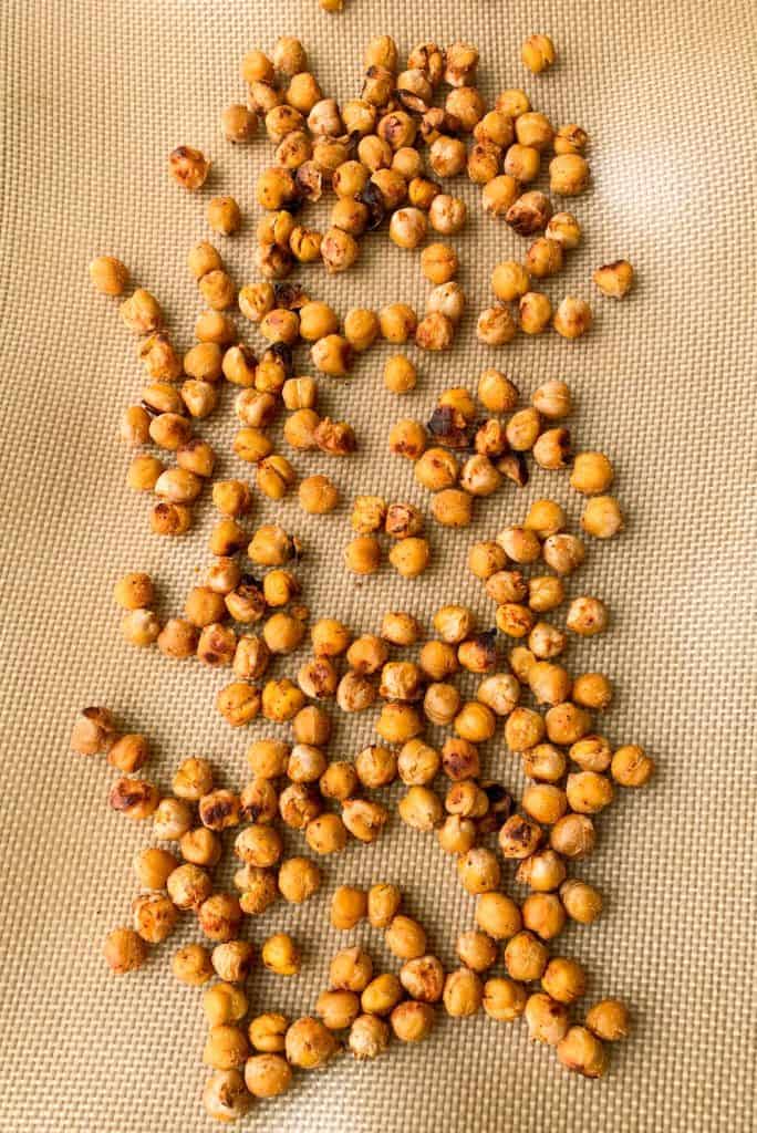 Top view and close up of roasted chickpeas spread out on a silicone baking mat 