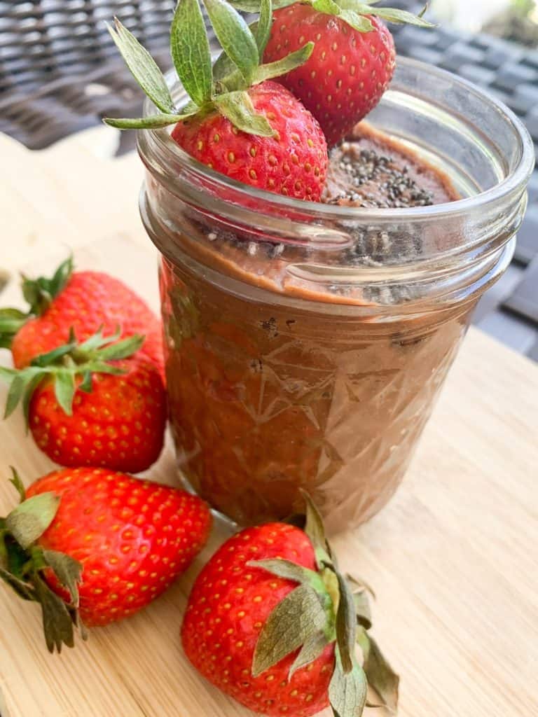 small mason jar with chocolate hummus topped with fresh strawberries and chia seeds
