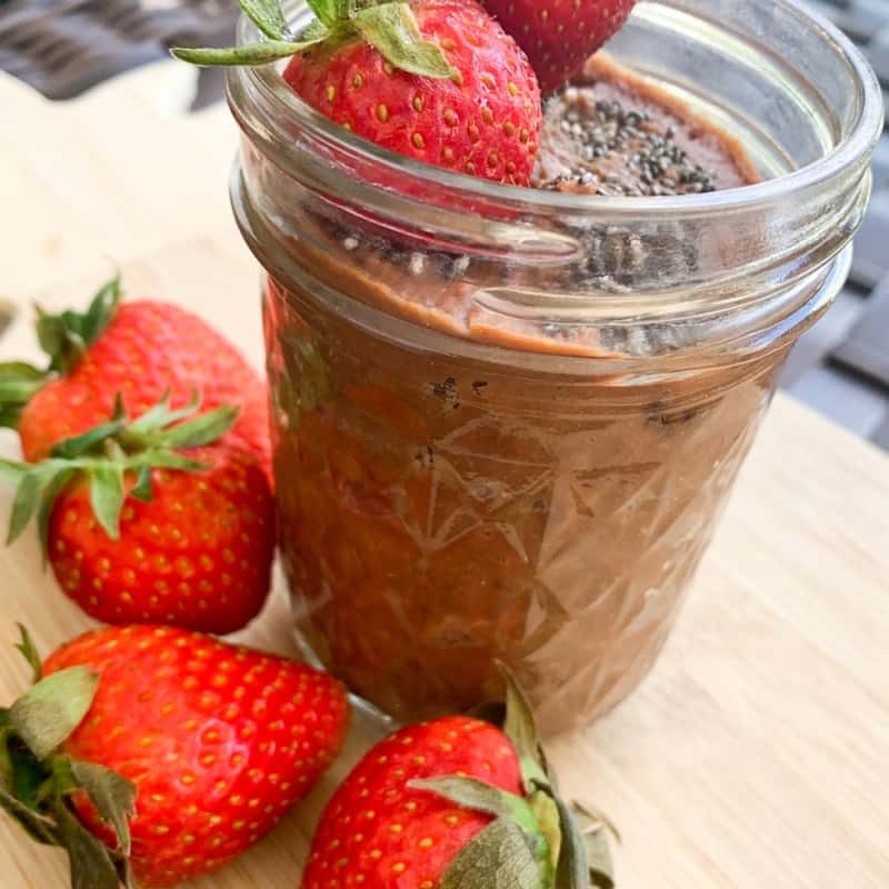 clear jar with chocolate hummus, fresh strawberries and chia seeds on top