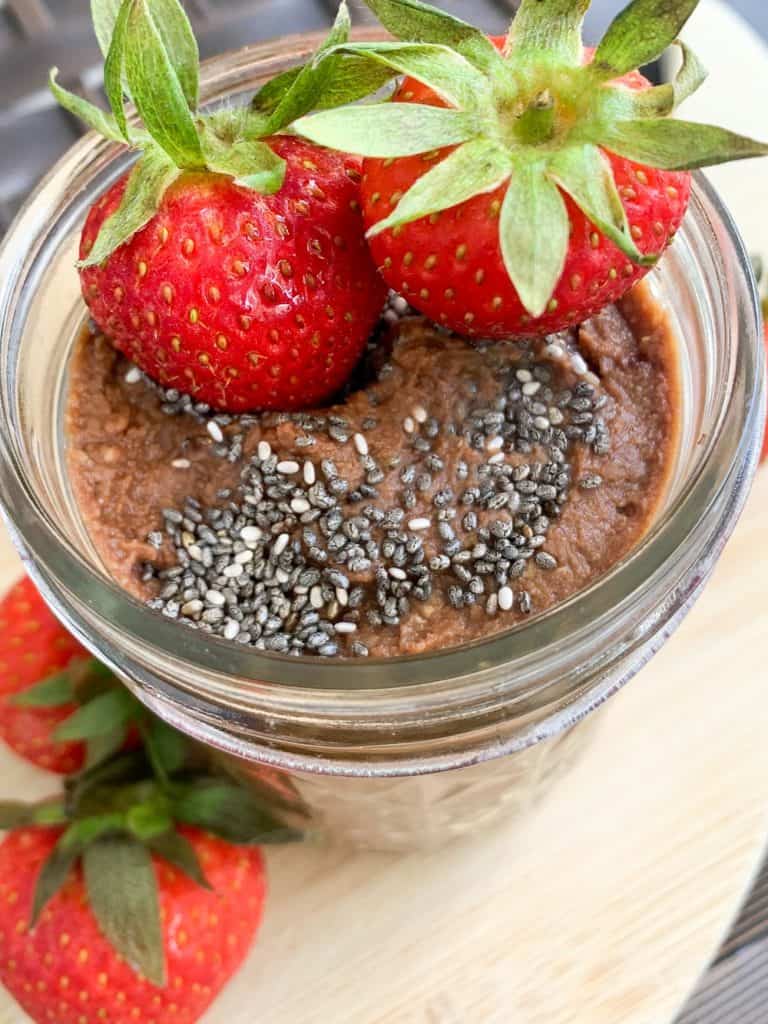 small mason jar with chocolate hummus topped with chia seeds and fresh strawberries