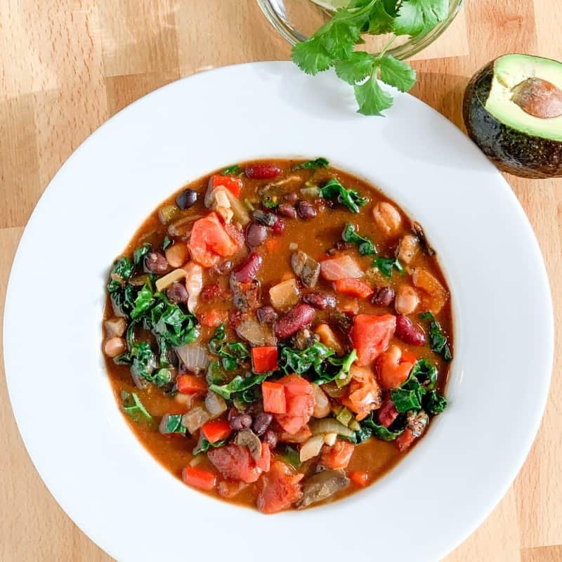 veggie chili in a white rim bowl, cilantro and avocado