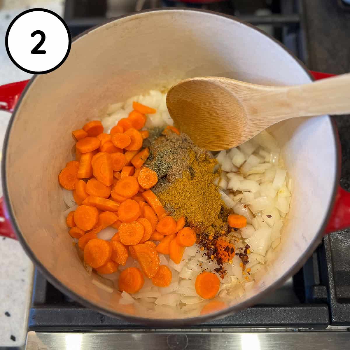 Onions, garlic, carrots and spices in a pot on the stovetop.