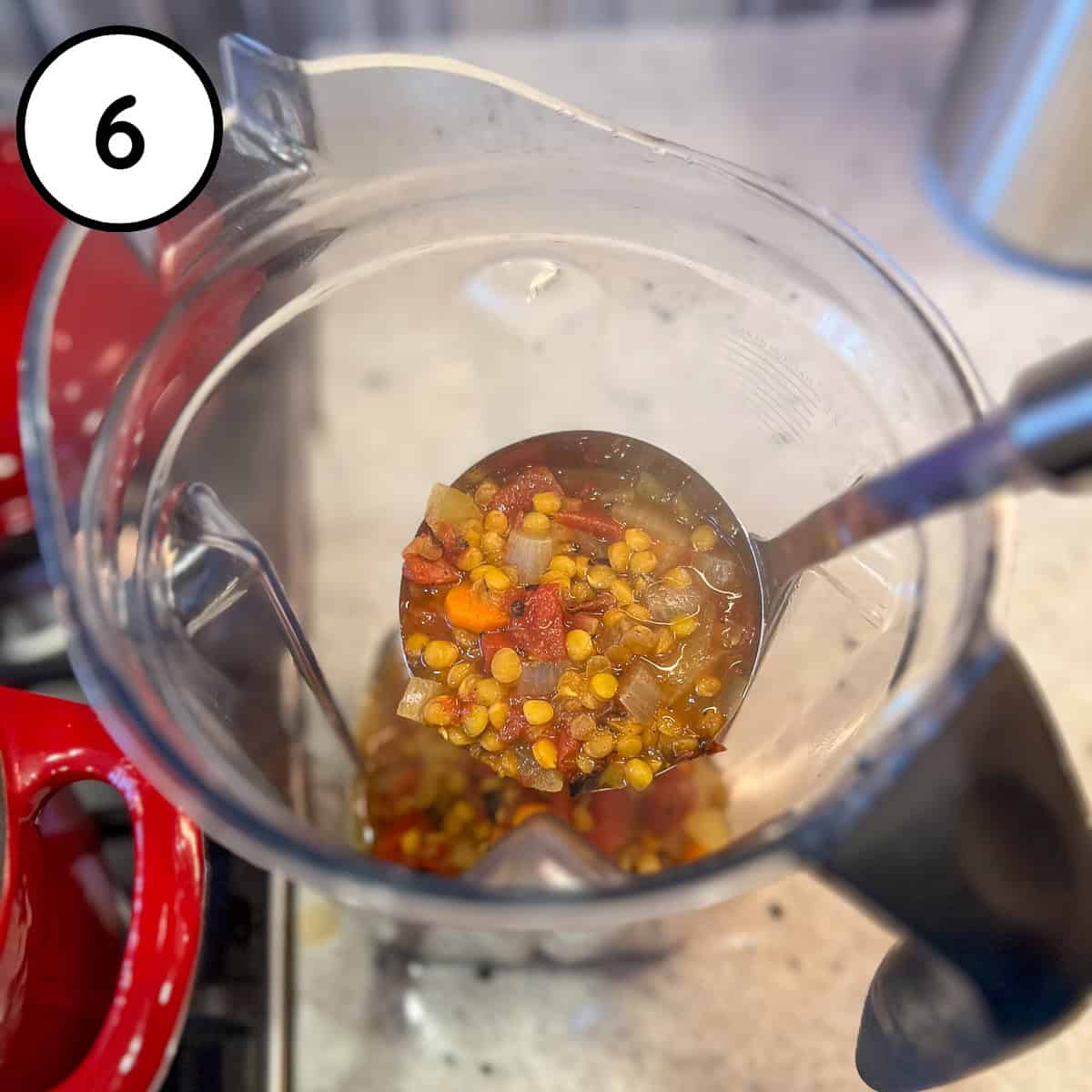 Soup being ladled into a blender pitcher. 