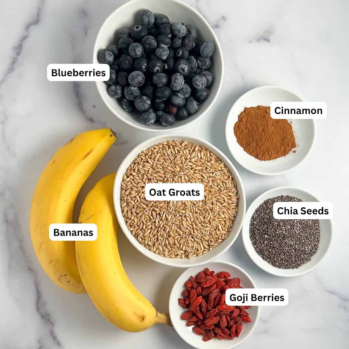 Ingredients for Oat Groats breakfast bowl: blueberries, bananas, oat groats, cinnamon, chia seeds, and goji berries.