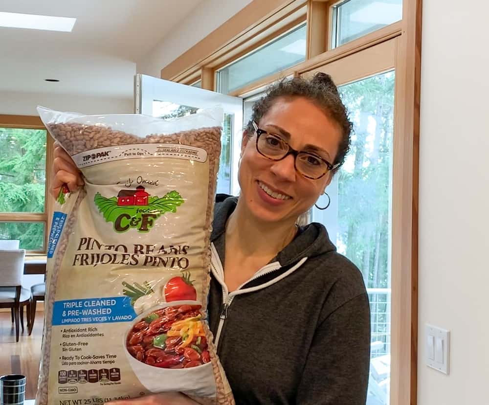 photo of Gigi holding a 25 pound bag of pinto beans she bought from Costco used to make refried beans (oil free)