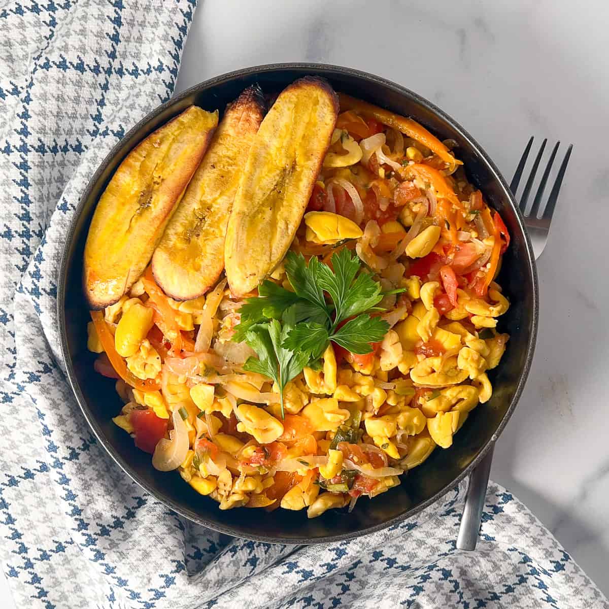 Vegan ackee in a bowl with fresh parsley and air fryer plantains.