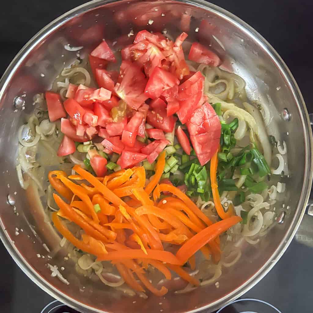 Bell pepper, chopped tomato and scallions added to the sauté pan with onions and garlic.