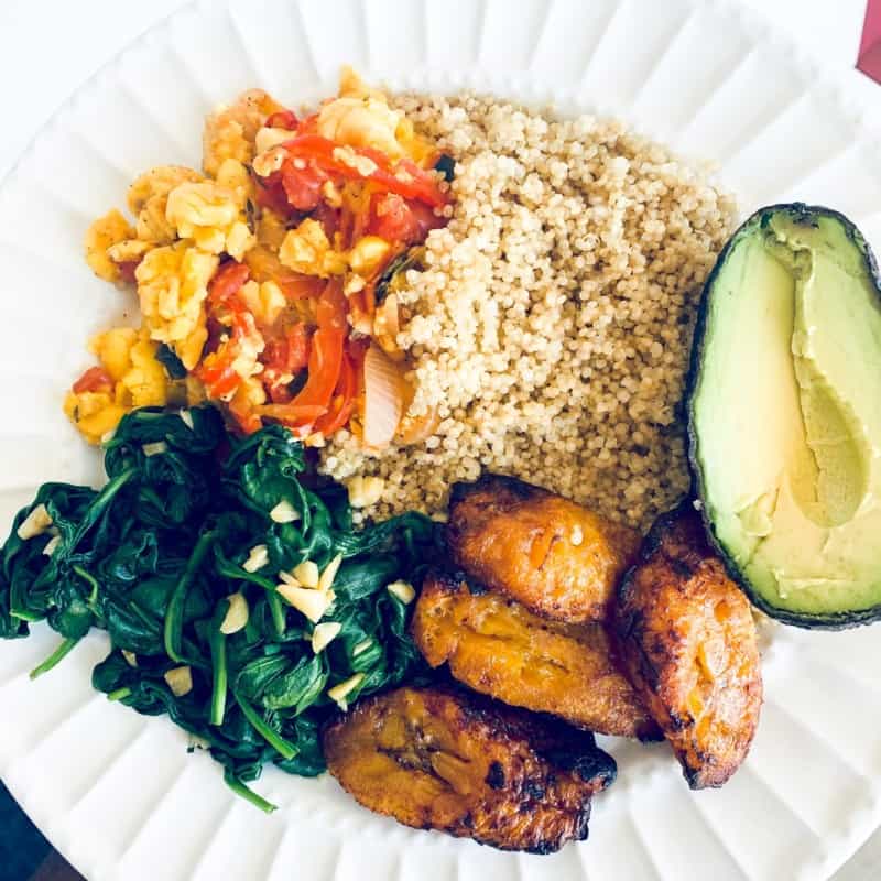 top view close up of vegan ackee dinner on a white plate with ackee, quinoa, avocado, plantains and spinach