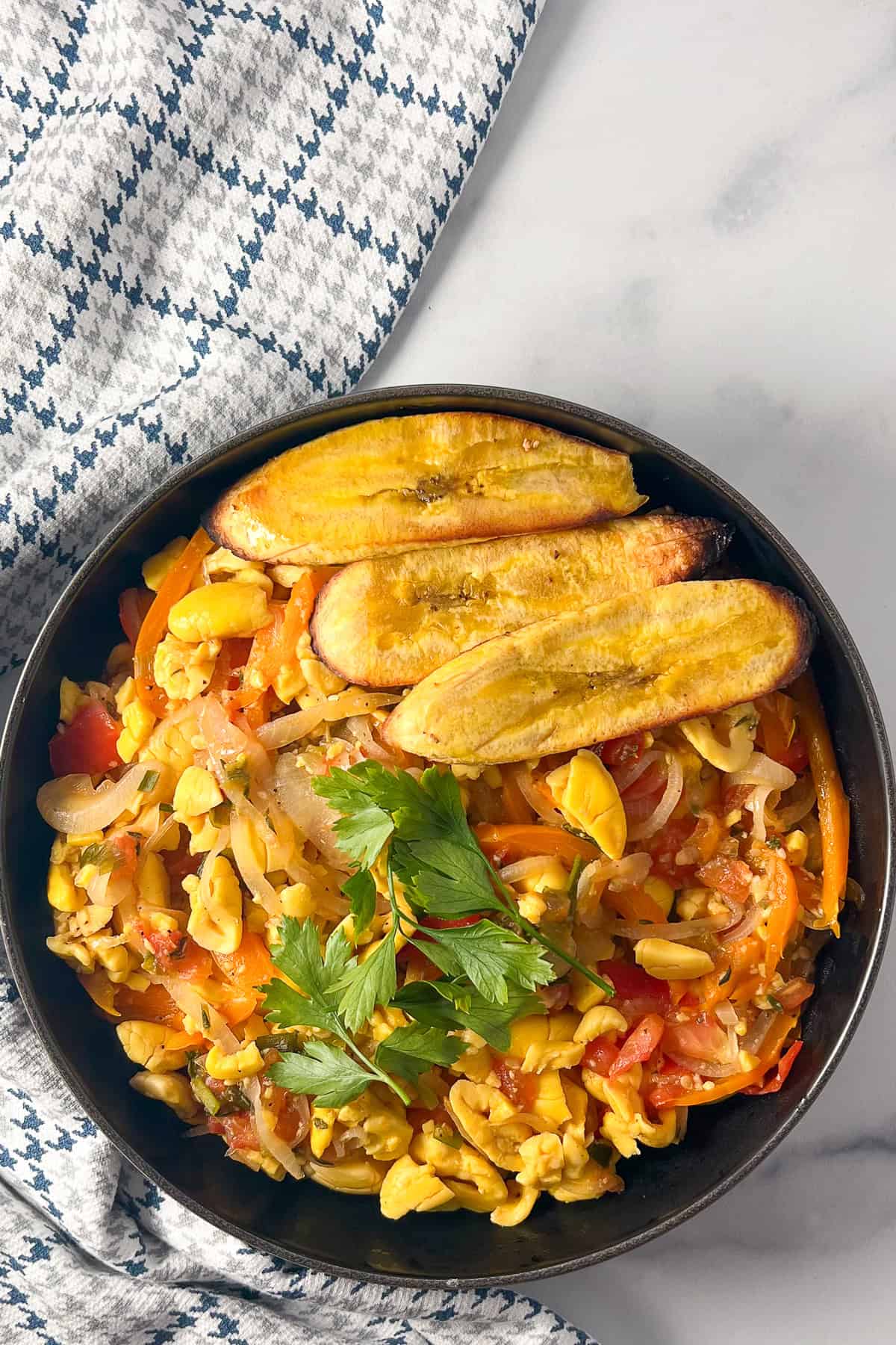 Vegan Ackee in a bowl with air fryer plantains and fresh herbs.