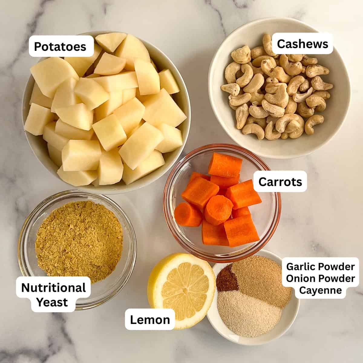 The ingredients for vegan cheese sauce: potatoes, cashews, nutritional yeast, carrot, lemon and seasonings.