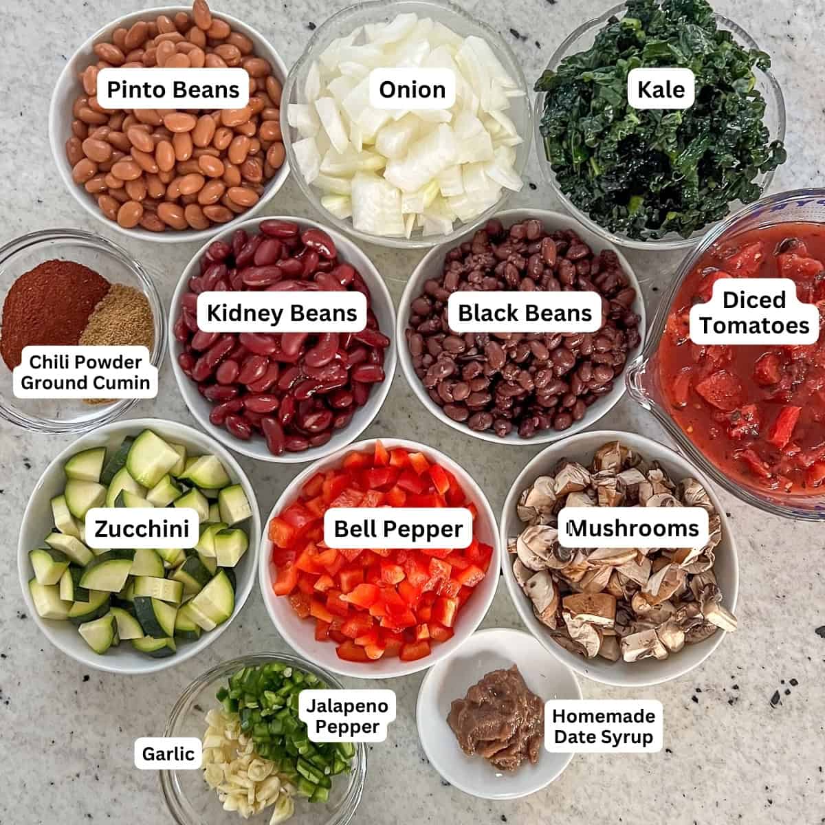 Ingredients for veggie chili: beans, onions, bell pepper, garlic, mushrooms, jalapeno, zucchini, tomatoes, kale and spices.