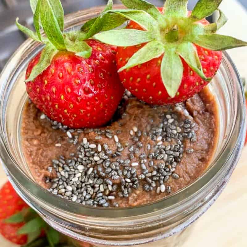 Chocolate hummus in a mason jar topped with fresh strawberries and chia seeds.