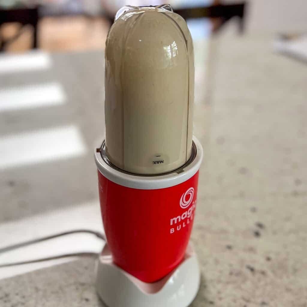 Lemon tahini dressing being blended in a mini bullet blender.