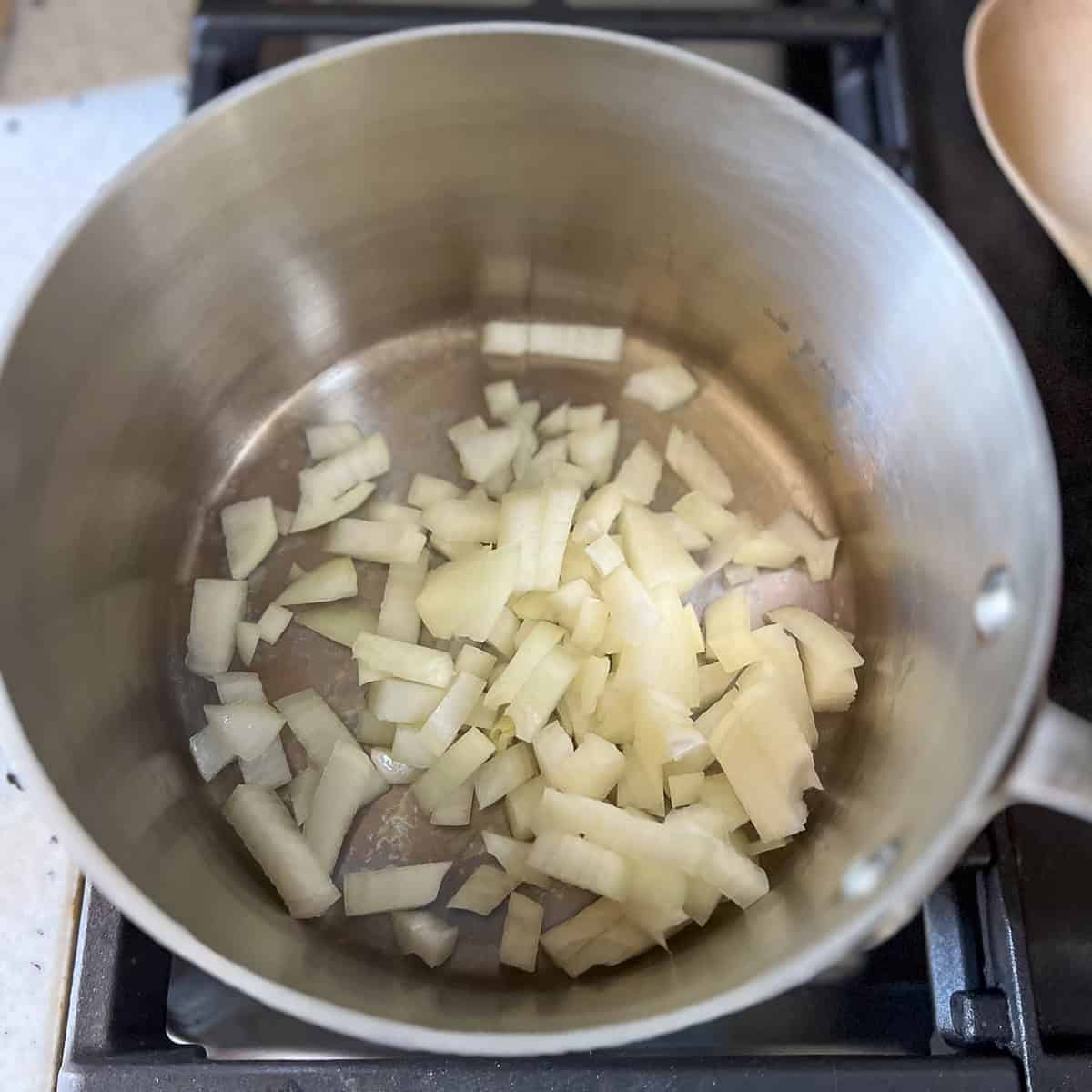 Chopped onions sauteing in a pot.