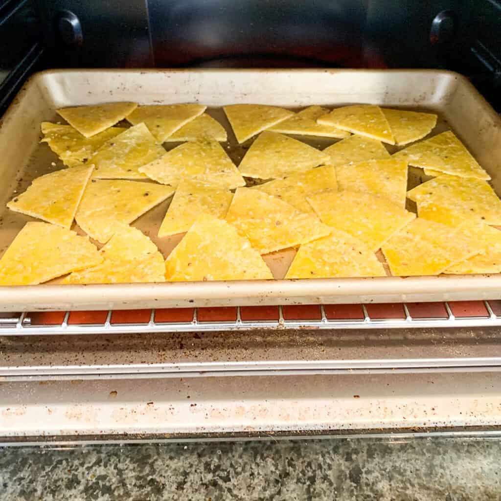 Oven baked tortilla chips in a baking sheet going into the oven.