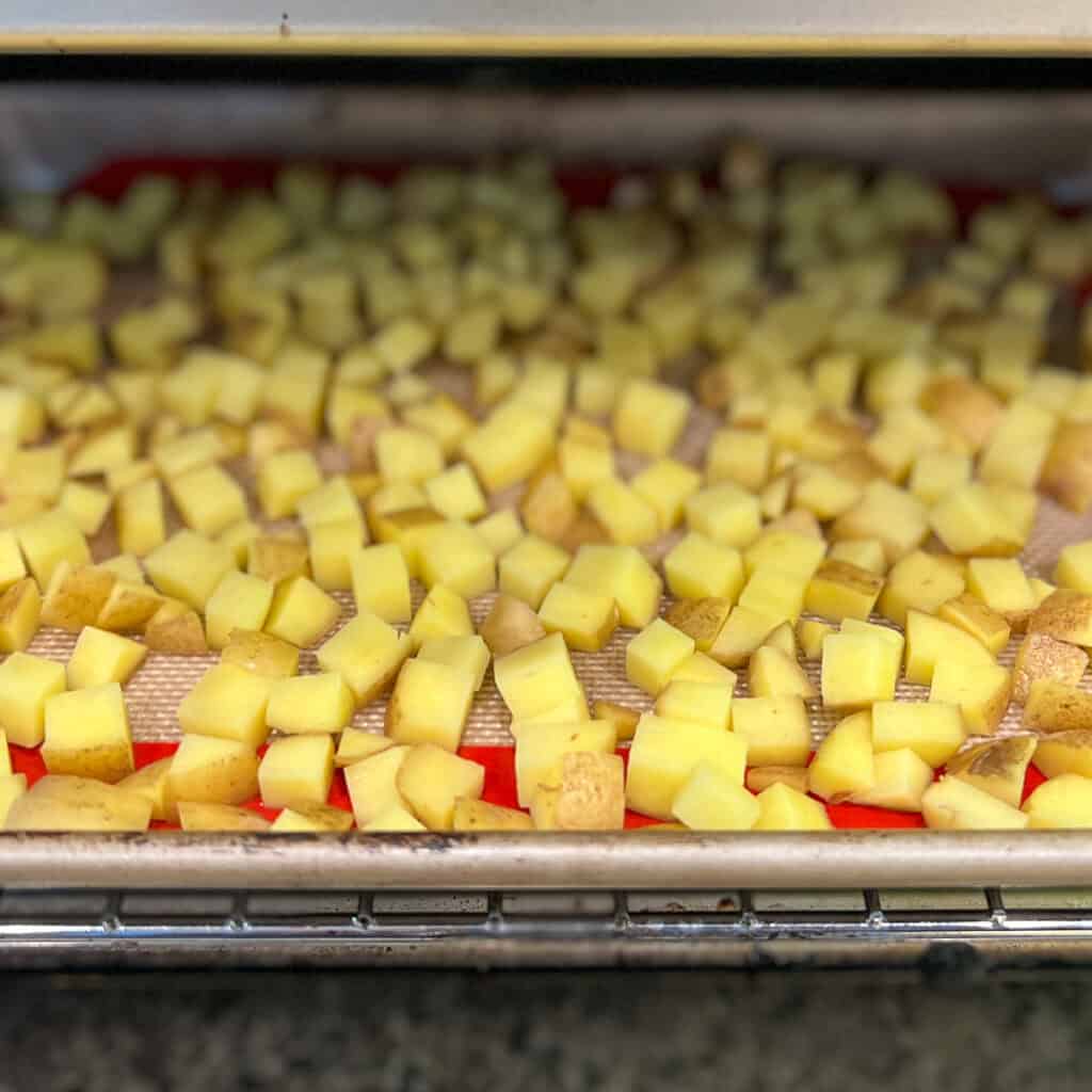 Diced potatoes on a baking sheet going into the oven.