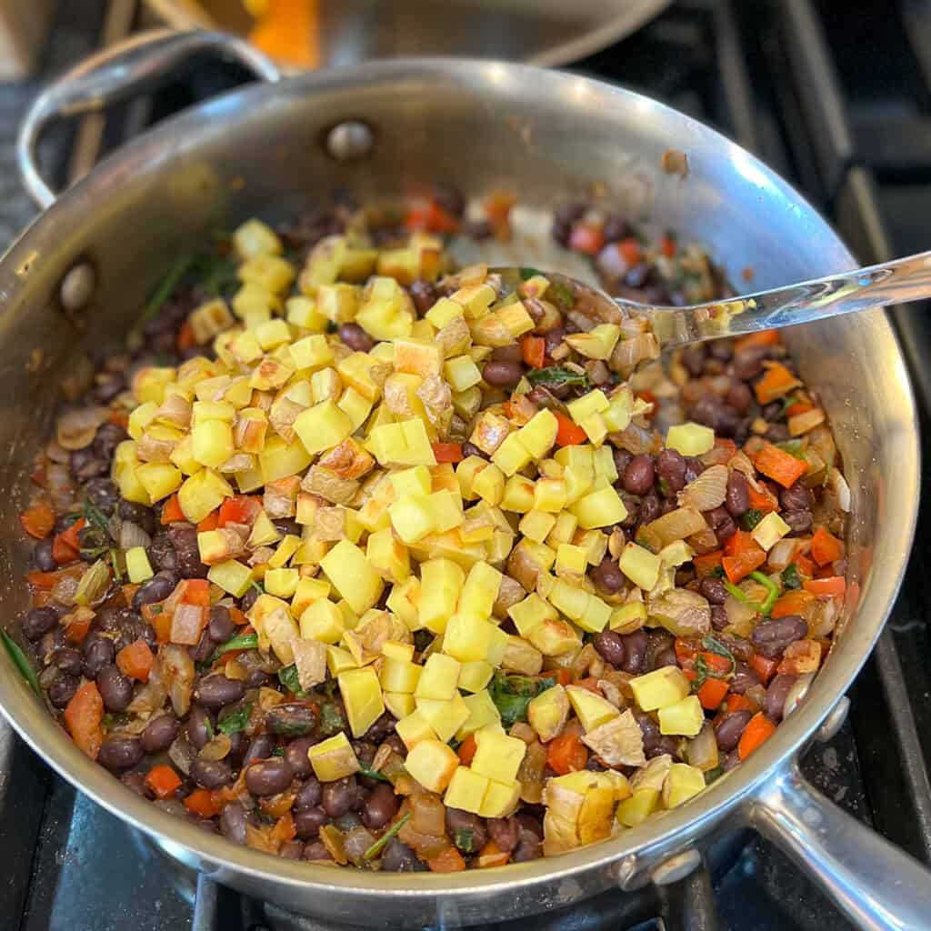 Cooked diced potatoes added to the sauté pan with beans and veggies.