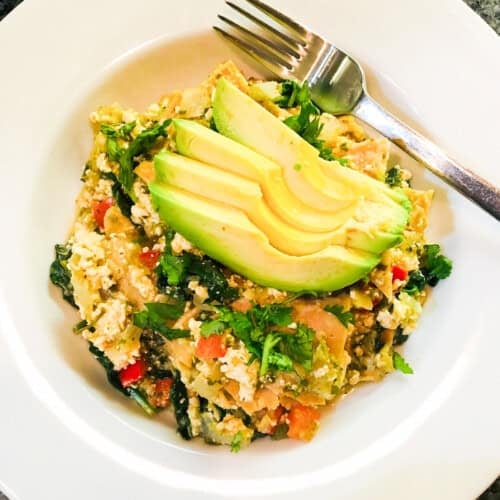 Vegan chilaquiles topped with fresh sliced avocado.
