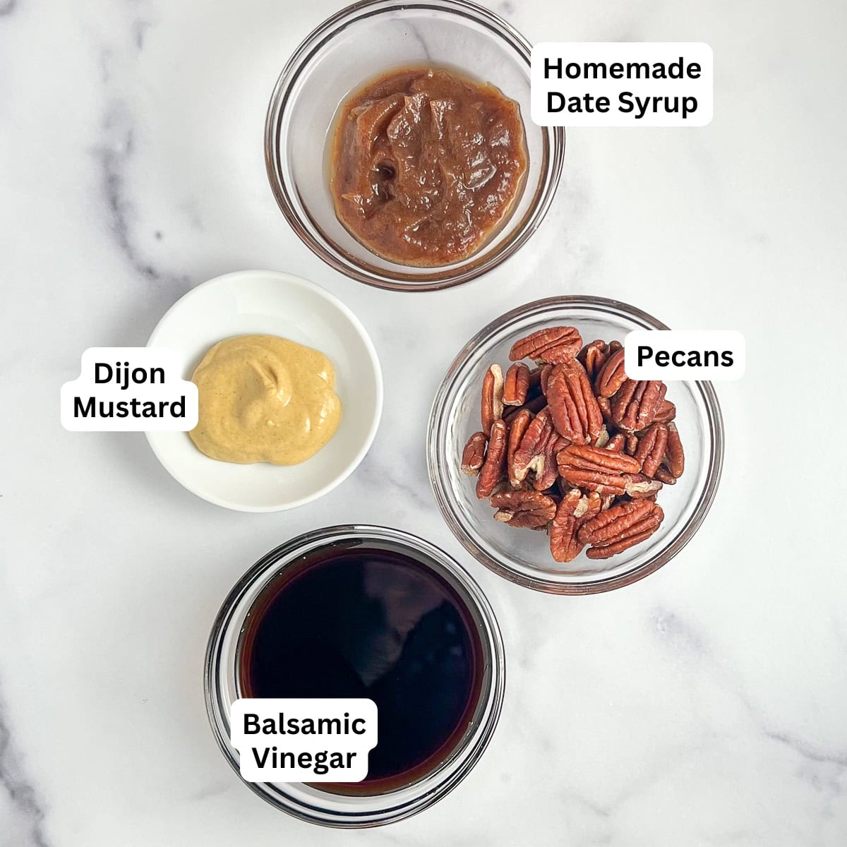 Ingredients for healthy balsamic vinaigrette dressing: homemade date syrup, Dijon mustard, pecans, balsamic vinegar.