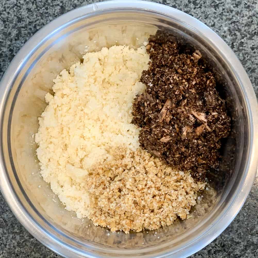 Top view of the key ingredients in vegan magic meat: cauliflower, mushrooms and walnuts in a large stainless steel mixing bowl.
