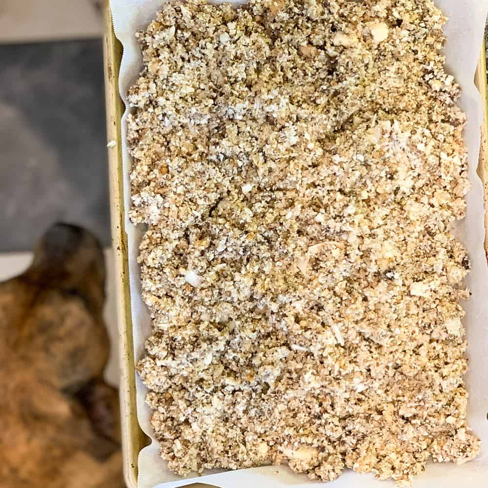 sheet pan lined with parchment paper and magic meat ingredients combined and spread evenly across sheet pan. in the background is Bree the dog.
