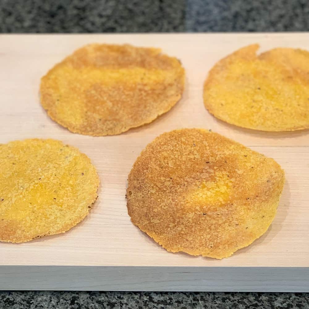 four oven baked corn tortilla for magic meat and bean tostadas sitting on a wooden cutting board