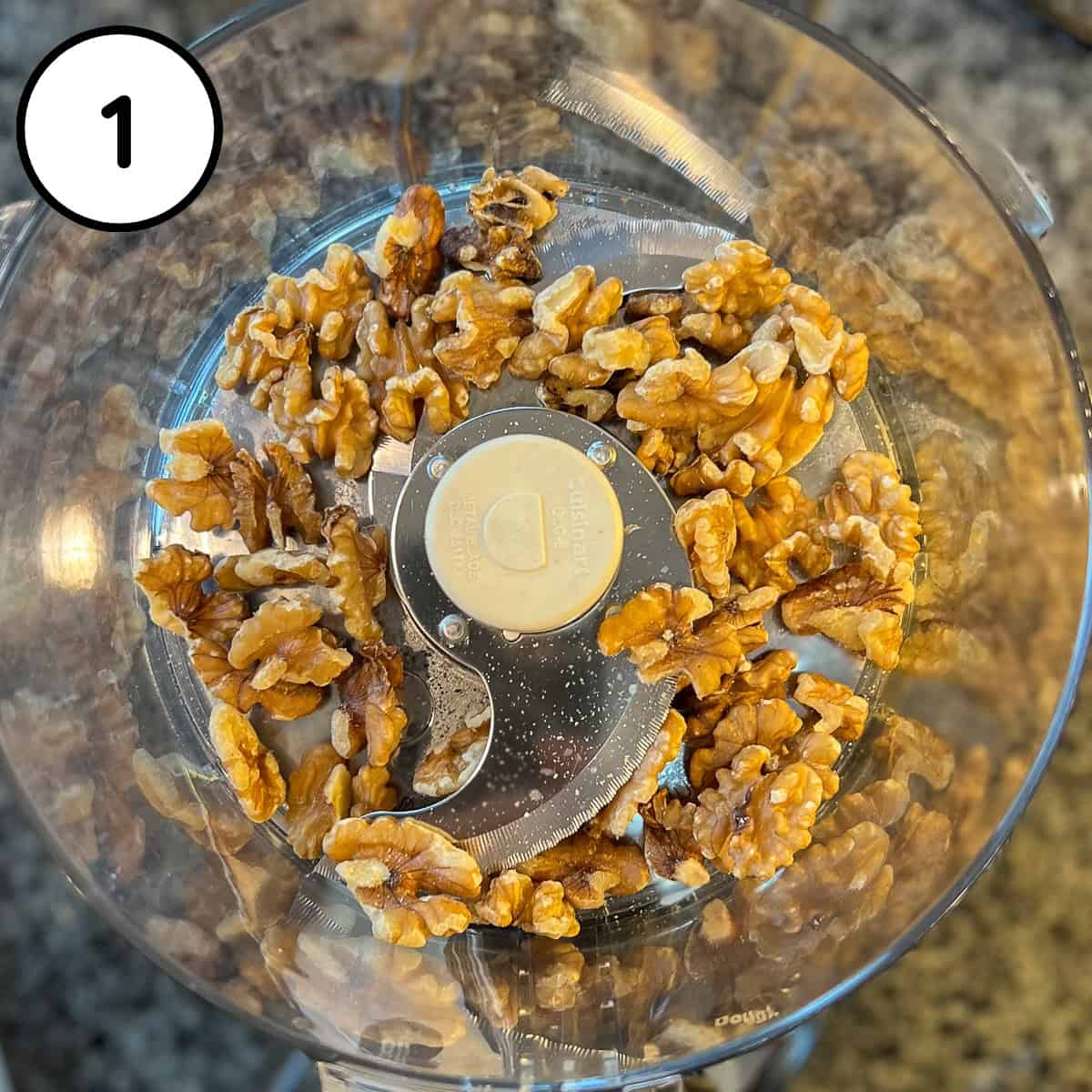 Raw walnuts in a food processor bowl before processing.