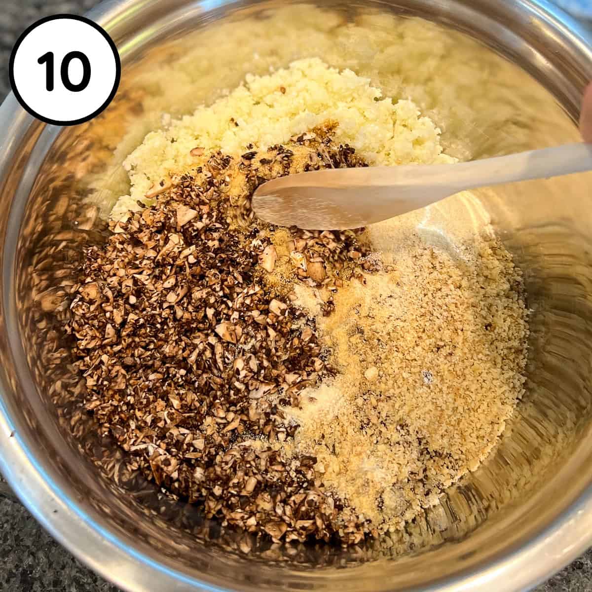 A wooden spoon combining in the walnut meat mixture in the mixing bowl.