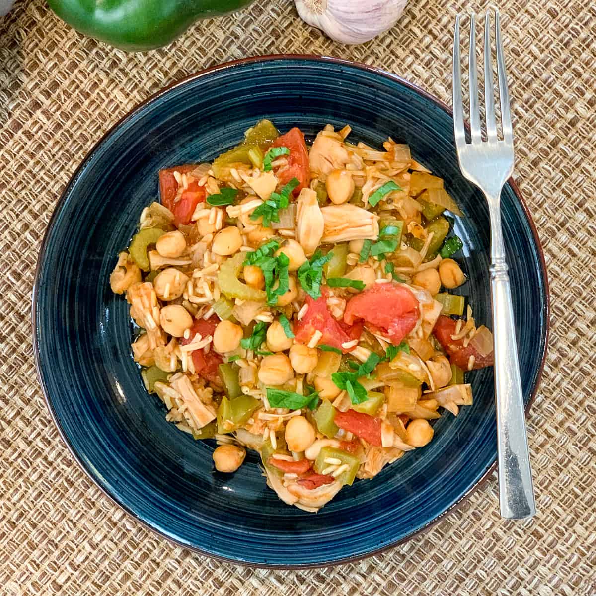 top view of jackfruit jambalaya in a dark blue bowl with fork on the side