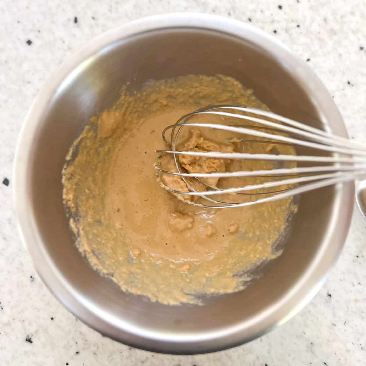 Kale and avocado salad dressing being mixed in a small mixing bowl with a whisk.