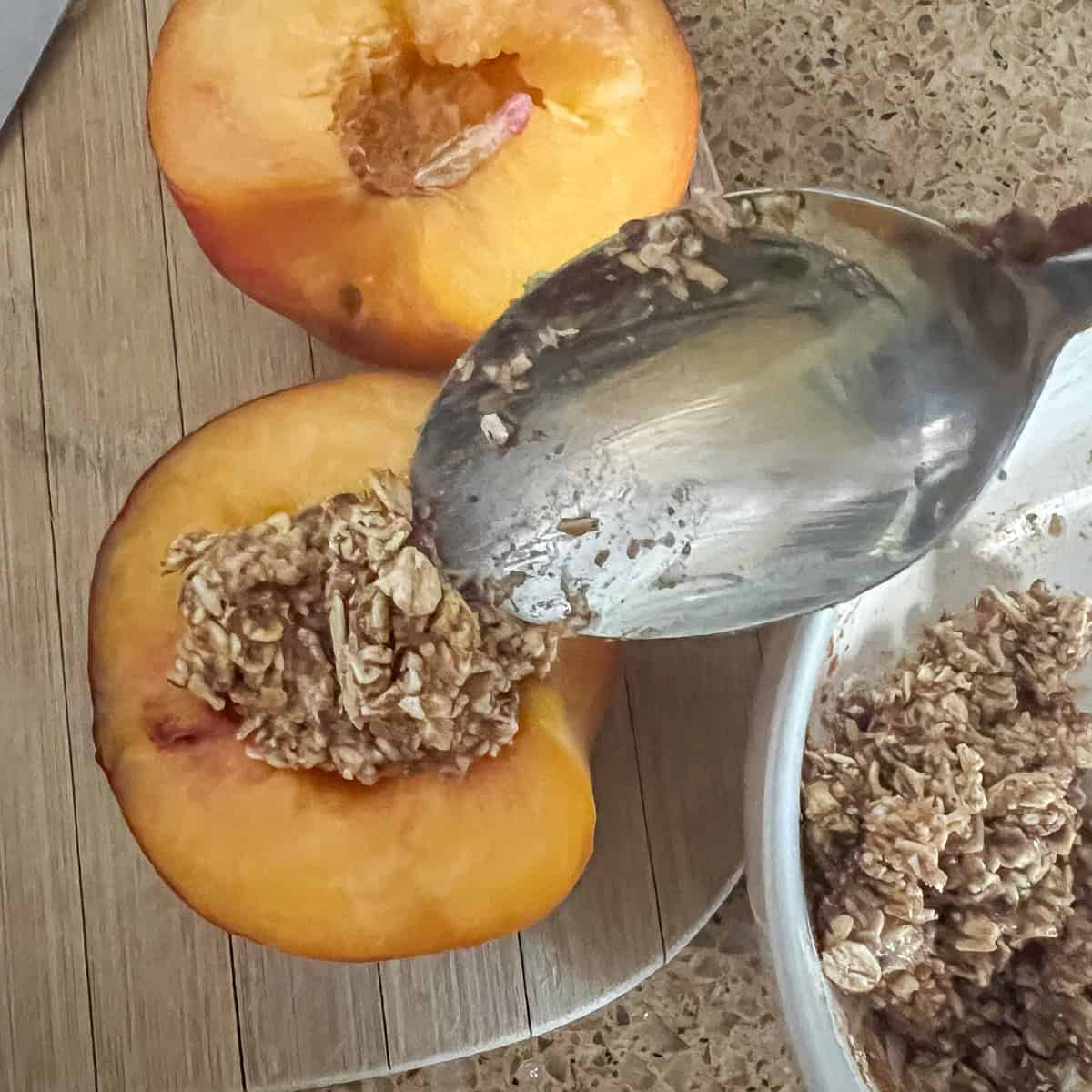 Oat mixture being added to the peach halves.