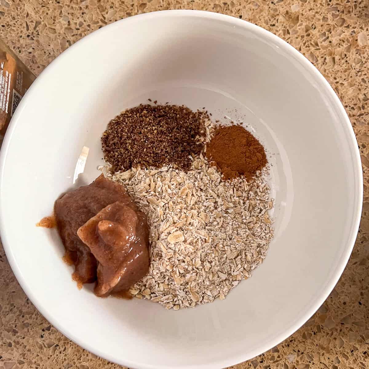 Ground oats, date syrup, ground flaxseeds and cinnamon in a bowl.