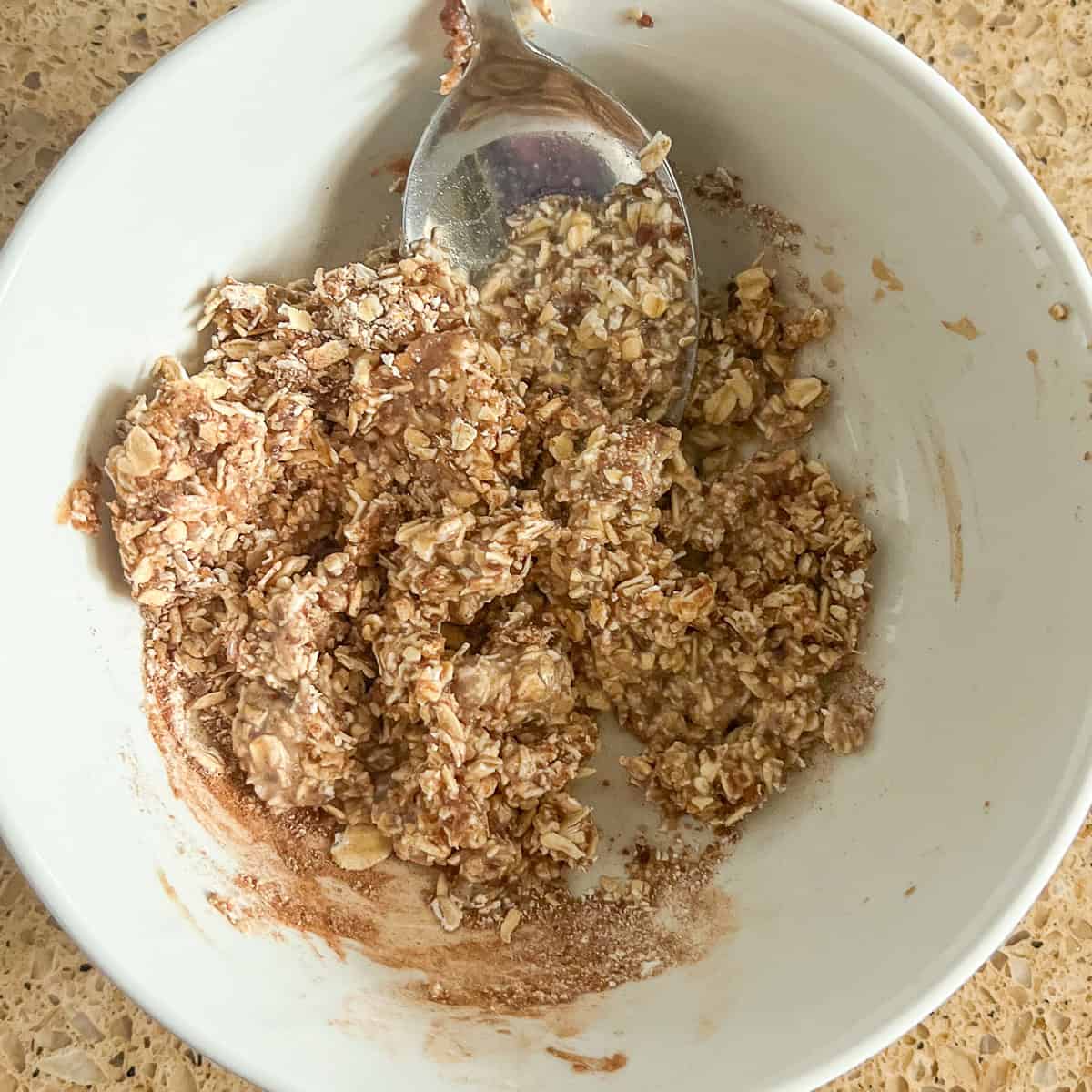 Oat mixture being stirred with a spoon.