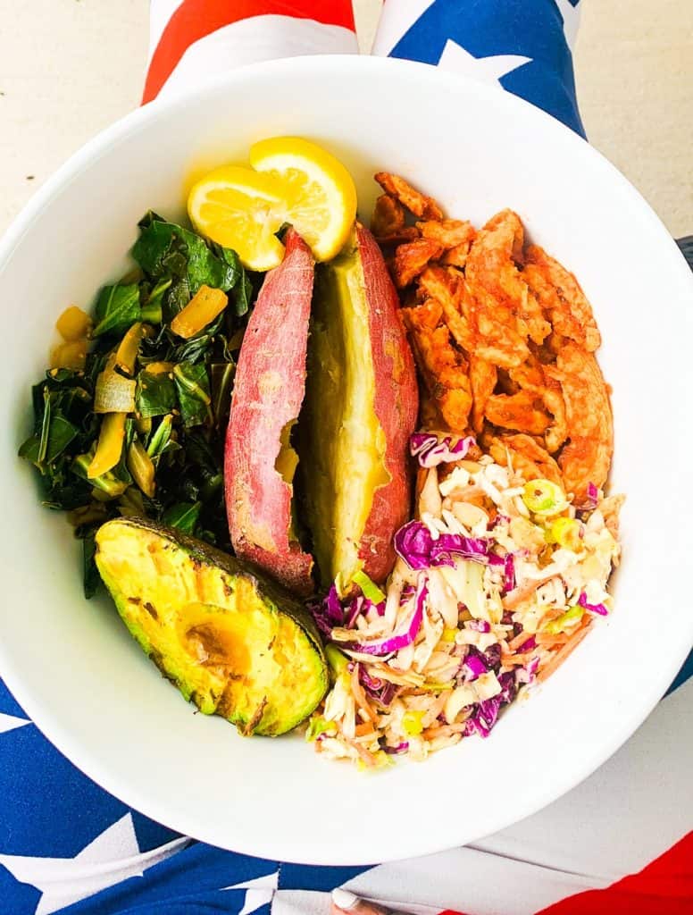 Top view close up of Sersie's All American Bowl with bbq soy curls, japanese sweet potato, collard greens, asian slaw and grilled avocado in a white bowl