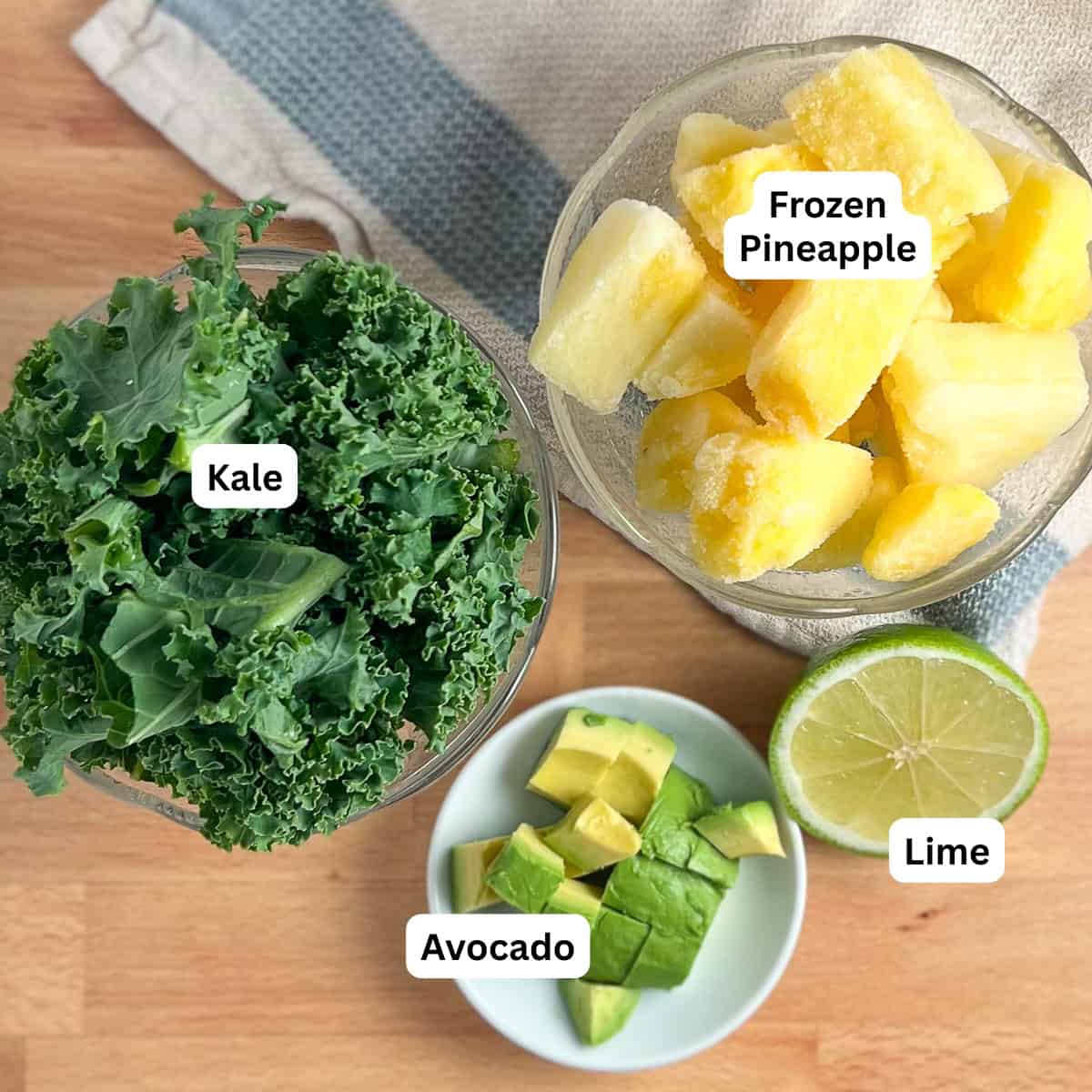 Ingredients for kale smoothie: kale, frozen pineapple chunks, avocado, lime.
