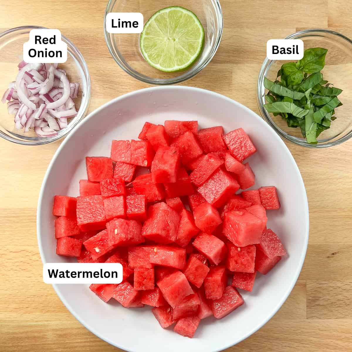 Watermelon basil salad ingredients: watermelon, chopped onion, half lime, and chopped basil.