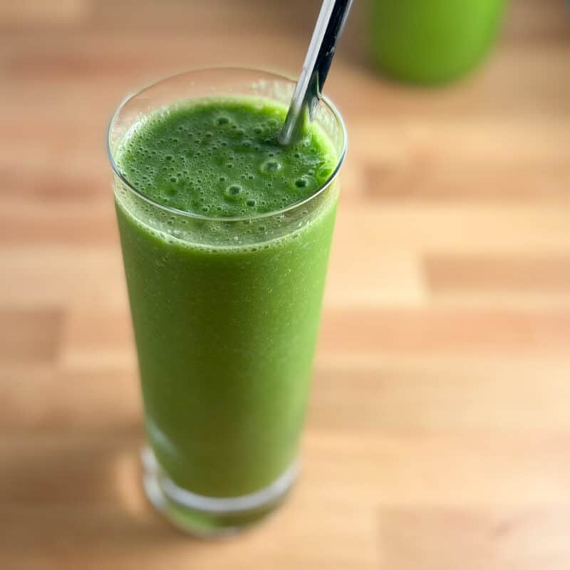 side top view close up of kale smoothie in tall glass with metal straw