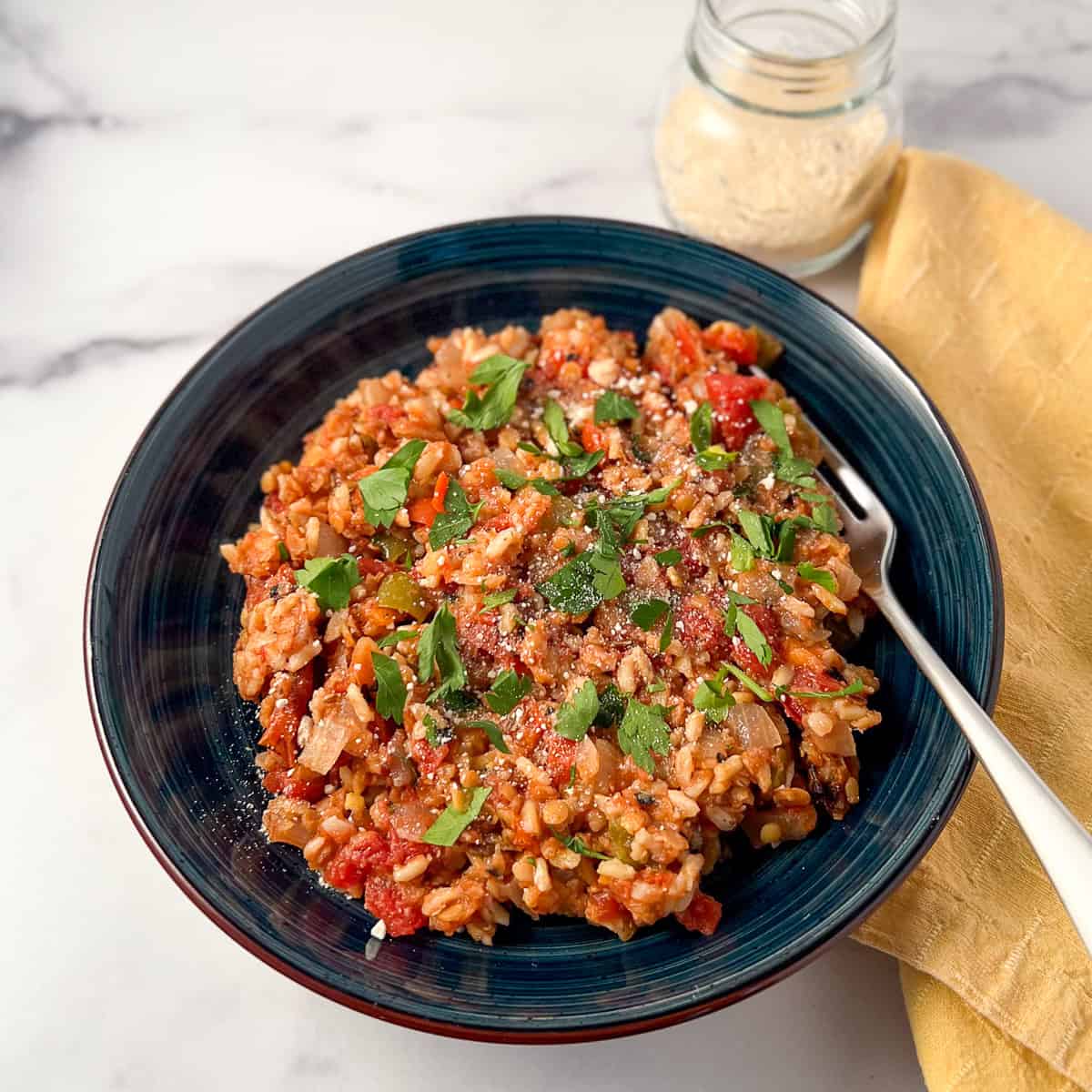 Cashew parmesan cheese sprinkled on top of a bowl of deconstructed stuffed peppers.