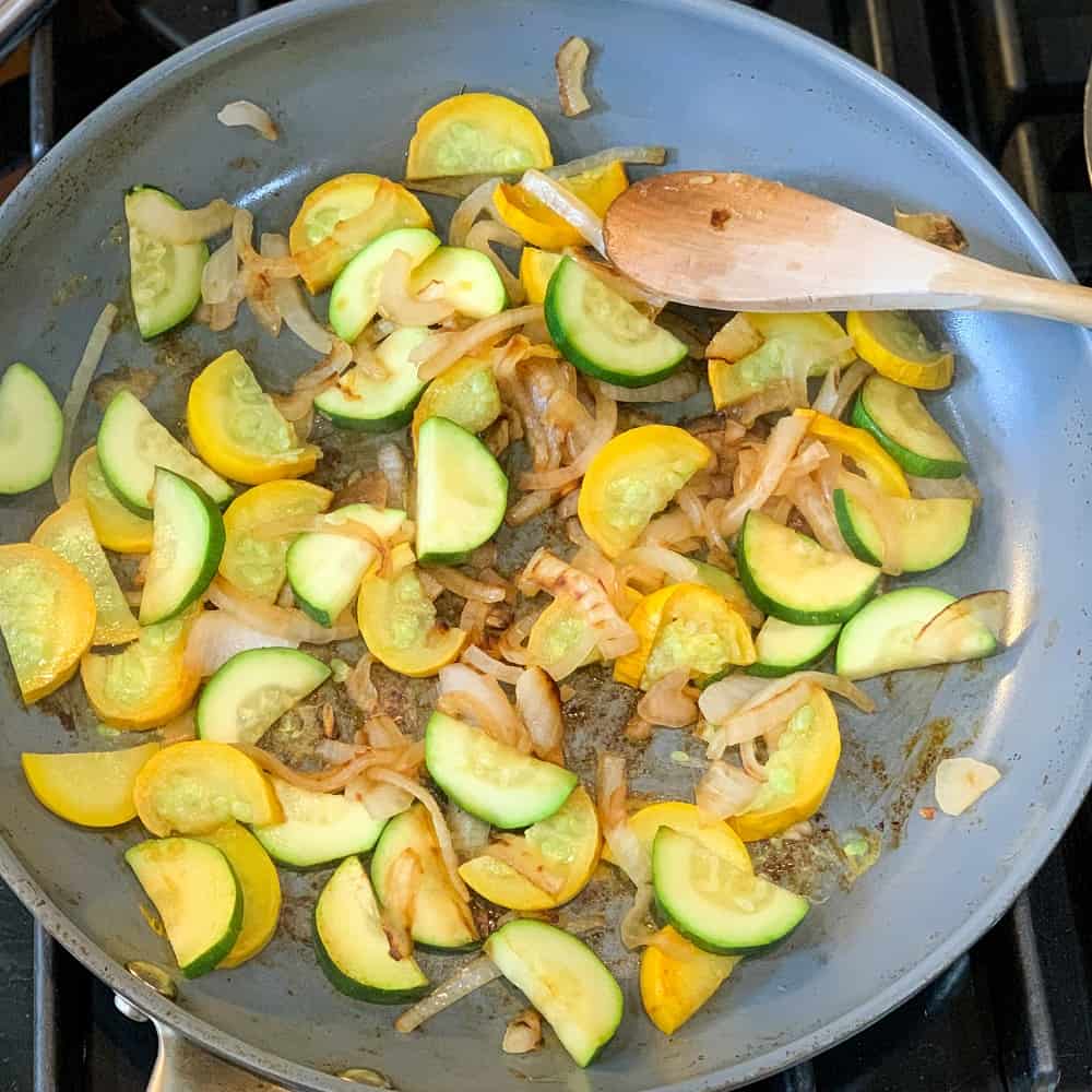 top view close up of onion and summer squash being dry sautéed in a non-stick skillet
