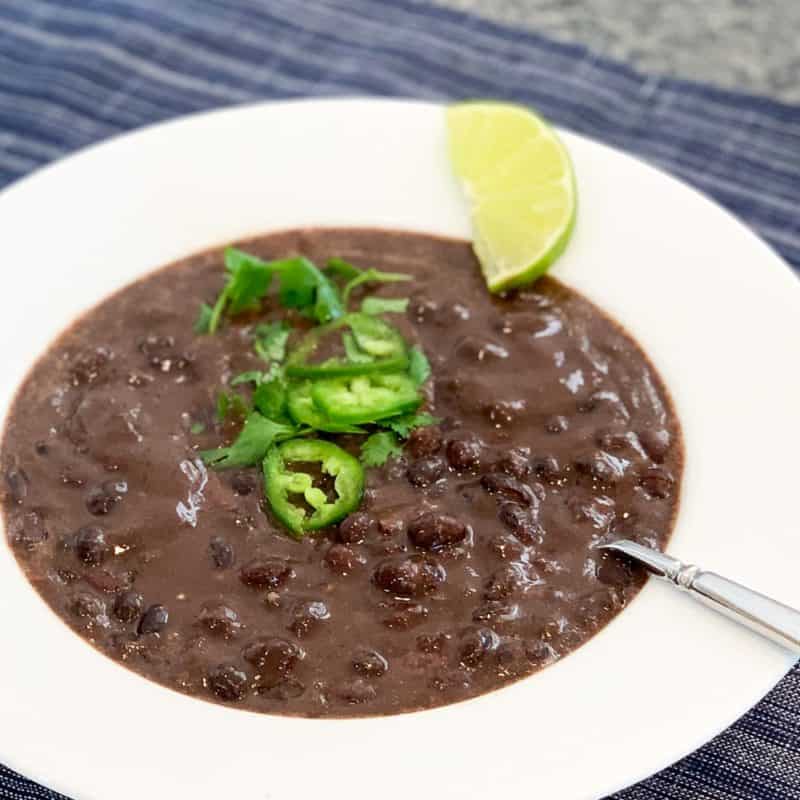 close up of 7-Minute Quick and Easy Black Bean Soup in a white bowl on a dark blue placemat