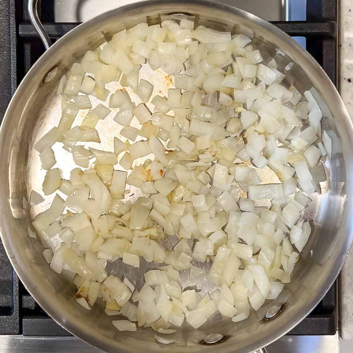 Chopped onions sautéing in a pan.