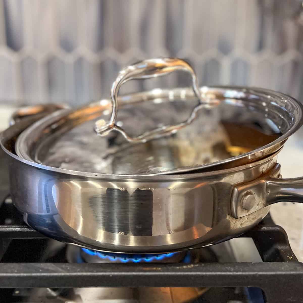 Partially covered sauté pan on the stovetop.