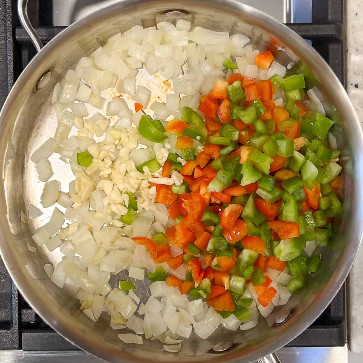 Chopped bell pepper and garlic added to the pan with sauteed onions.