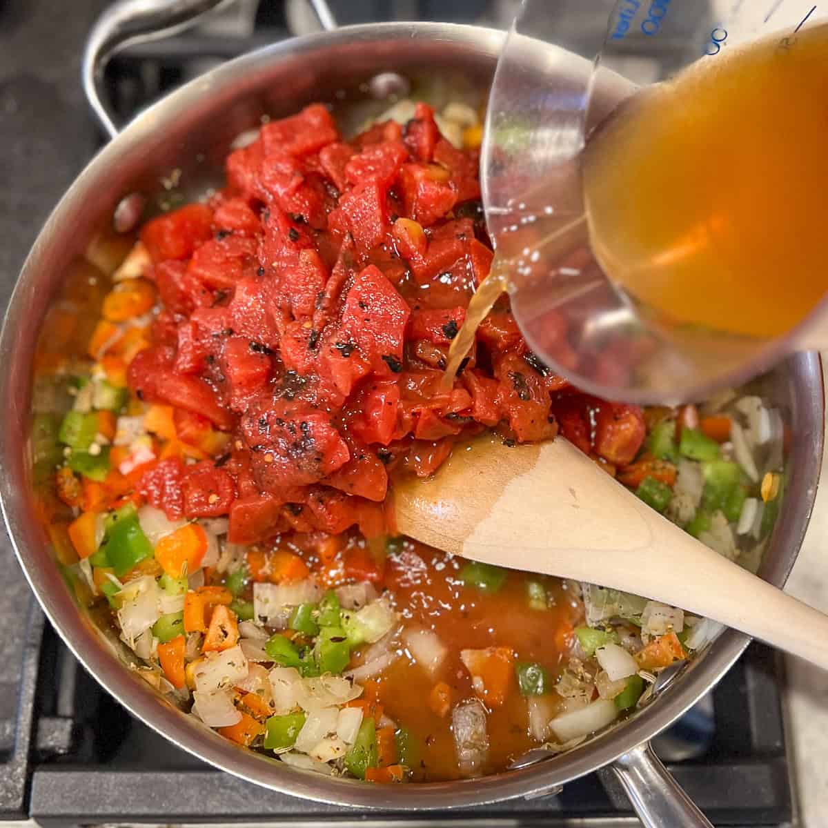 Fire roasted diced tomatoes and vegetable broth added to the pan with veggies.