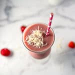 Copycat starbucks pink drink topped with coconut flakes and a straw.